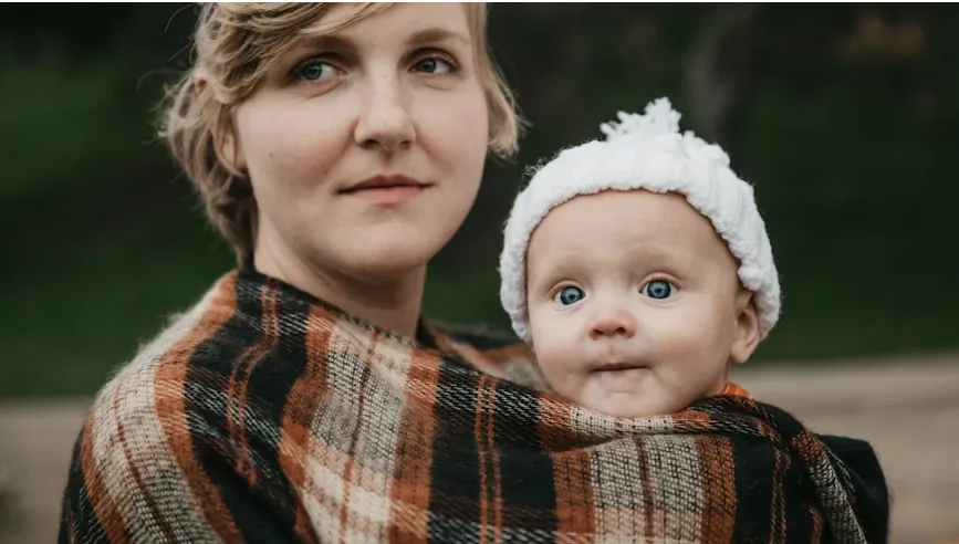 A mother holding her baby in a wrap
